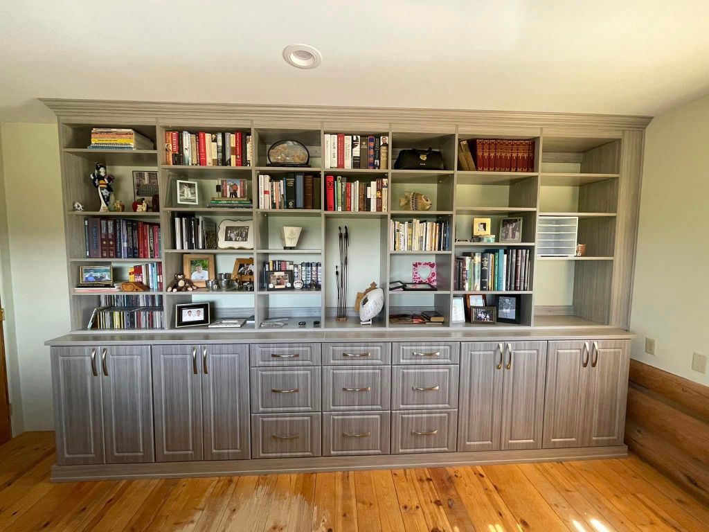 Concrete bookshelves unique space in home office, with raised panel drawer & door fronts, matte gold hardware, and crown molding to ceiling, build a custom library custom shelving in your home, Colorado best custom bookcases, closet factory, california closets, cali closets, mountain closets, aspen best closet designers