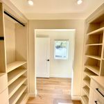 Arctic walk-in closet with flat drawer fronts, black hardware, full backing, crown to ceiling.