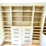 Arctic walk-in closet with flat drawer fronts, black hardware, full backing, crown to ceiling, full length mirror.